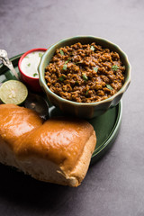 Kheema / keema Pav or Khima Paav is a spicy curry dish made up of minced chicken or lamb cooked with onion, tomatoes, served with buns. selective focus