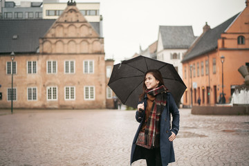 Beautiful lady is holding an umbrella in the rainy day