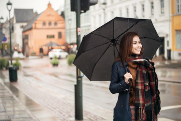 Beautiful lady is holding an umbrella in the rainy day