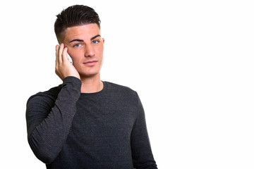 Studio shot of young handsome man talking on mobile phone