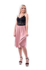 Cocky young classy woman beauty in pink skirt lifting skirt smiling and looking away. Full body isolated on white background. 