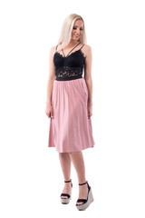 Attractive blonde young woman in elegant evening wear smiling and looking down. Full body isolated on white background. 