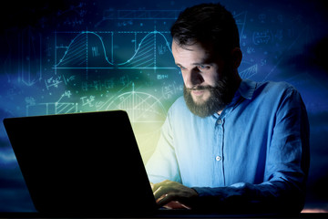 Young handsome businessman working late at night in the office with blue mathematic charts in the background