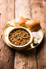 Kheema / keema Pav or Khima Paav is a spicy curry dish made up of minced chicken or lamb cooked with onion, tomatoes, served with buns. selective focus