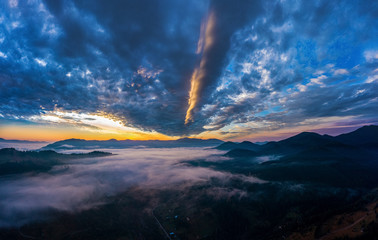 Naklejka na ściany i meble Aerial view amazing sunrise over of the Carpathian Mountains or Carpathians with the village under fog.