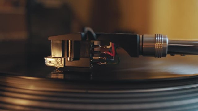 Close up side view on needle on rotating vinyl disc on dj music turntable record player