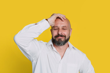 Handsome serious middle aged man meditate on yellow background with copy space.