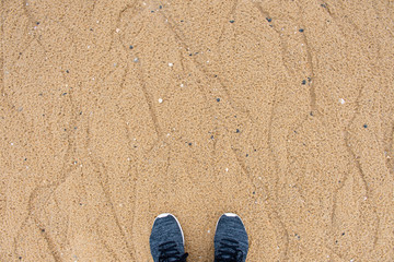 Fototapeta na wymiar Top view of selfie sport shoes standing on the sand in the beach.