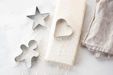 Raw puff pastry dough lies on a white table. Figures for baking cut metal mold. Copy space, top view.