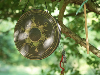 gong hanging on a branch of a tree in a garden for spiritual rituals, sound therapy 