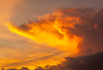 Panorama of thunderstorm clouds lit up in the colors of sunset.