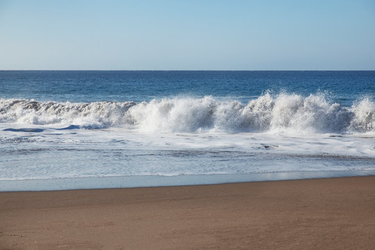 Frothy large waves braking on Playa La Tejita, a kilometre-long wild and tranquil beach, near Montana Roja Nature Reserve, a favorite attraction for water sports, in Tenerife, Canary Islands, Spain