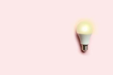 Creative concept of a luminous energy-saving light bulb on a pink background. Energy conservation or idea