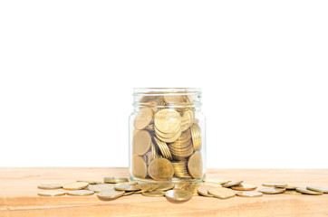 golden coin in glass jar on wood table against white background. money saving concept for business financial banking investing.