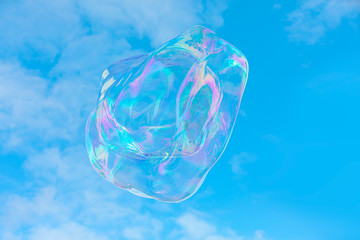 Fototapeta premium Blowing big soap bubbles in the air against blue cloudy sky