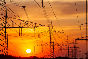 Freileitungsmast vor  orangefarbenen Himmel