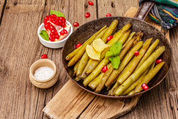 Baked green bean in pan with sesame seeds, pomegranate, mint and lemon