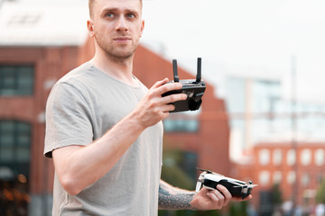 Obraz na płótnie Canvas Young handsome man launching drone quadcopter at urban background. cityscape. modern device.