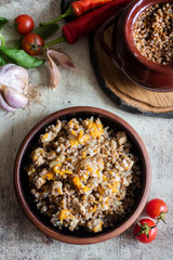 Buckwheat porridge with meat in plates and puts on a gray background. Vertical photo