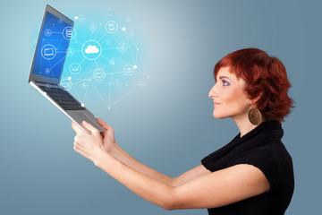 Woman holding laptop projecting cloud based system symbols and informations
