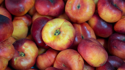 High-angle view of a pile of delicious ripe and juicy Chinese flat peaches of platycarpa variety, also known as Saturn doughnut, doughnut peaches, paraguayo or pan tao peaches at the Farmer's market