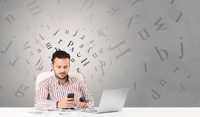 Business person sitting at desk with editorial and letters concept