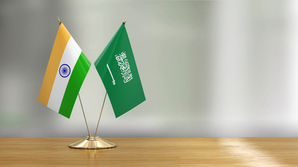 Saudi Arabia and Indian flag pair on a desk over defocused background 