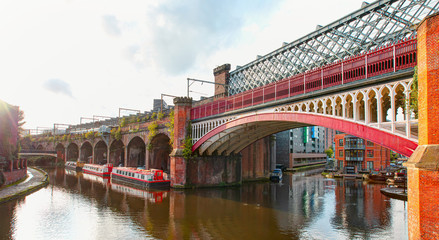 Waterway canal area with a narrowboat on the foreground modern bridge, Castlefield district