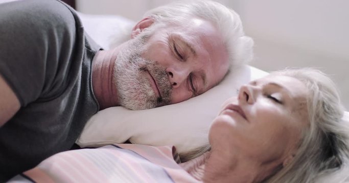 Senior Adult couple on holiday sleeping in hotel bed
