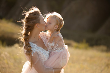 Portrait of a beautiful young mom holds her beloved daughter in her arms. Parental love, little...