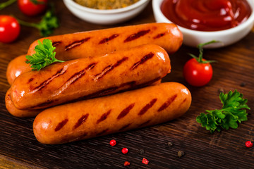 Grilled Smoked Hot Dogs Sausages on Wooden Background. Selective focus.