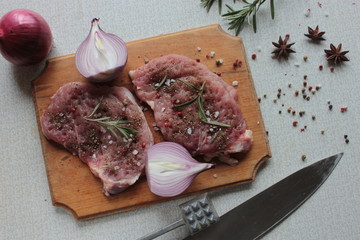 Fresh raw meat with spices on a wooden board.