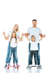 happy parents holding hands of son and daughter riding penny boards on white