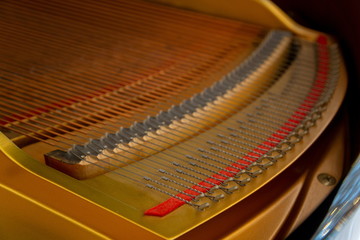 close up strings coil inside a gold wooden piano music instrument .
