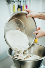 Male baker prepares dough for baking grain bread with flax seeds