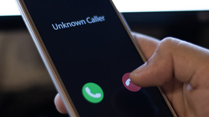 Unknown caller. A man holds a phone in his hand and thinks to end the call. Incoming from an...