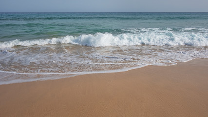 Fototapeta na wymiar Frothy waves washing the pristine beach Playa Jandia, in Fuerteventura, one of the most attractive tourist destinations in the Canary Islands, for its white sandy beaches, mild climate and wild nature