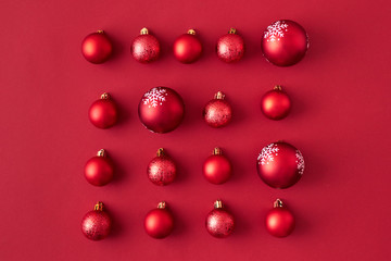 Flat lay pattern with red christmas balls on a red background