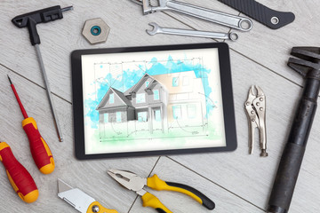 Tablet with construction tools and house plan concept