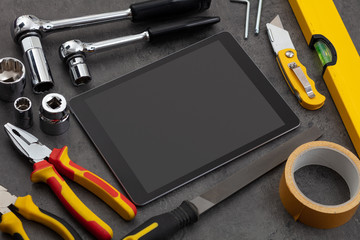 Tablet with empty screen and construction tools around