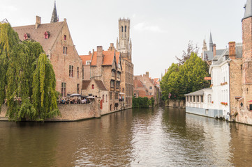 Fototapeta premium Bruges, Belgium. Medieval ancient houses made of old bricks at water channel with boats in old town. Picturesque landscape.