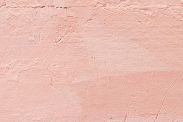 Wall unevenly painted in pink-coral color with scratches and cra