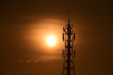 Telecommunication tower with orange sky.Telecommunication towers with TV antennas and satellite dish