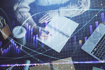 Forex graph on hand taking notes background. Concept of research. Double exposure
