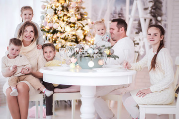 Big friendly family sits together at the New Year's table and looks at the camera