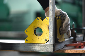 Worker is fixing a metal frame by magnetic square.
