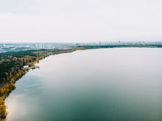 View of the lake from the height. Autumn by the lake. Panorama of the city and the forest.