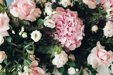 Close-up of roses and greenery wedding decor in sunlight.