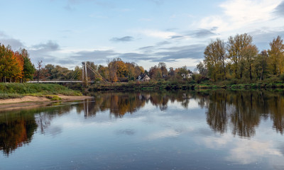 autumn landscape with river, bridge and beautiful colorful trees, river Gauja, Valmiera, Latvia