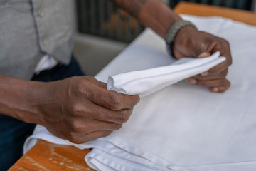Waiter folds napkins in restaurant. Waiters hands with white napkin closeup